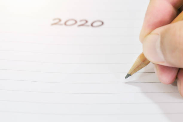 istock hand holds pencil in blank white paper notebook background 1181987075