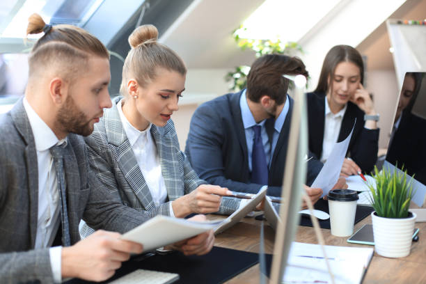 istock Group of young business people working, communicating while sitting at the office desk together with colleagues. 1181988185