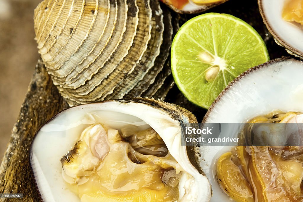 Raw Clams on a Half-Shell Fresh raw clams presented on the half shell with salsa and lime Bottle Stock Photo