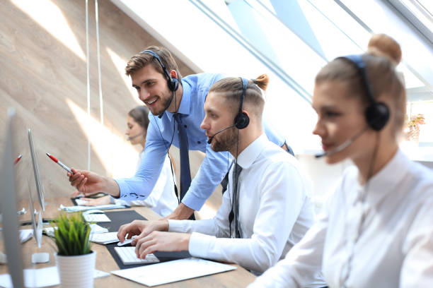 istock Phone operator working at call centre office helping his colleague. 1181989163