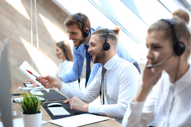 istock Phone operator working at call centre office helping his colleague. 1181989192