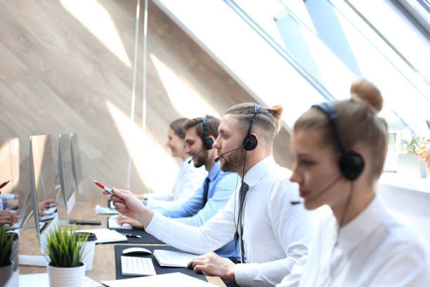 istock Portrait of call center worker accompanied by his team. Smiling customer support operator at work. 1181989258