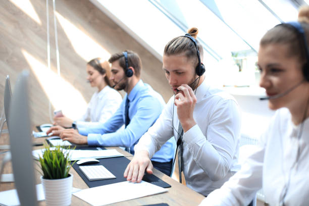 istock Portrait of call center worker accompanied by his team. Smiling customer support operator at work. 1181989308