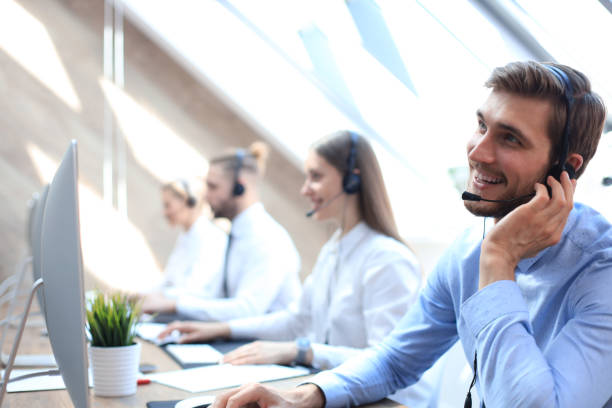 istock Portrait of call center worker accompanied by his team. Smiling customer support operator at work. 1181989903