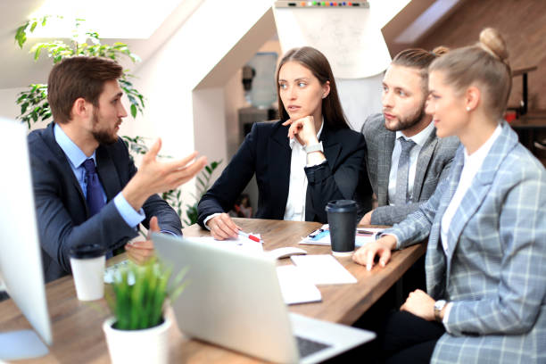 istock Group of young business people working, communicating while sitting at the office desk together with colleagues. 1181990239