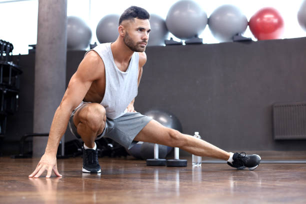 istock Man at the gym doing stretching exercises on the floor. 1181991194
