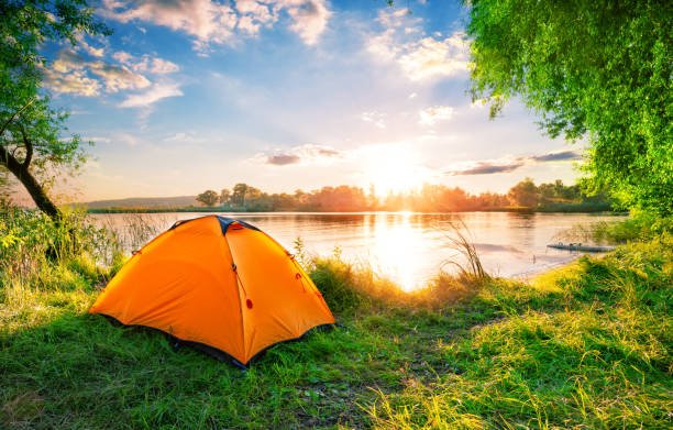 istock Orange tent on the lake at sunset 1181994756