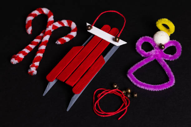 pipe cleaner craft candy canes and an angel, with a craft stick sled ornament with some red craft cord and tiny jingle bells. holiday crafts are a tradition for many families - scrapbooking office supply art and craft equipment scissors imagens e fotografias de stock