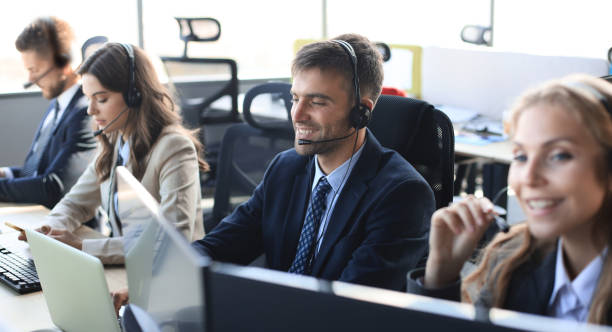 istock Portrait of call center worker accompanied by his team. Smiling customer support operator at work. 1181996781