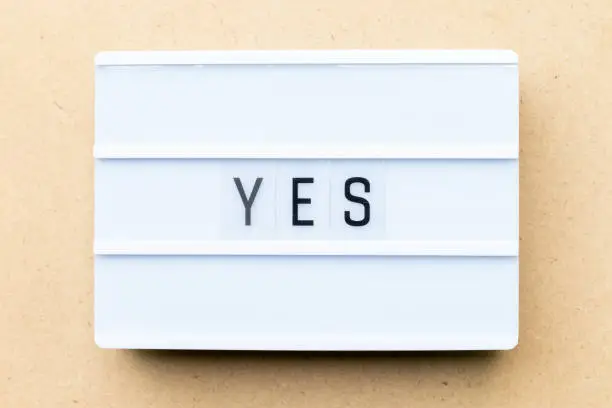 Photo of White lightbox with word yes on wood background