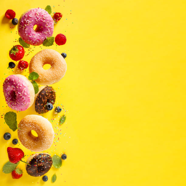 istock Various decorated doughnuts with sprinkles and berries in motion falling on yelloy background 1181999306