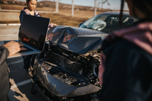 istock Mechanics looking at damaged car and using laptop 1182002371