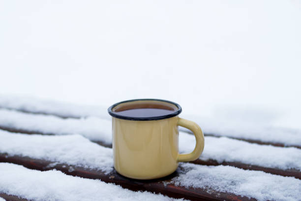 istock Metal cup with hot tea on a snow-covered bench in a winter park. 1182003723