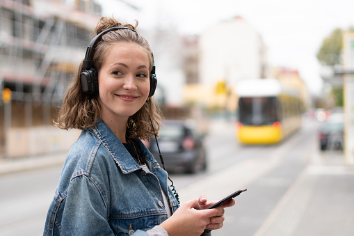 Girl with headphones listening to music waiting for the streetcar