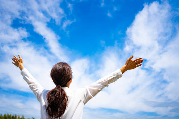 istock Woman spreading her hands towards the blue sky 1182010908