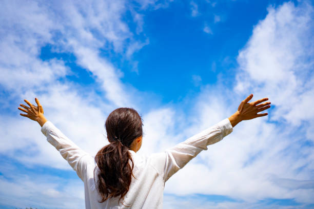 istock Woman spreading her hands towards the blue sky 1182010922