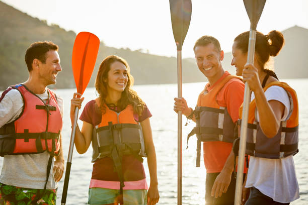 istock Happy friends with oars standing at riverbank 1182012077