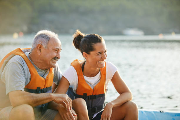 istock Happy father and daughter sitting at riverbank 1182012115