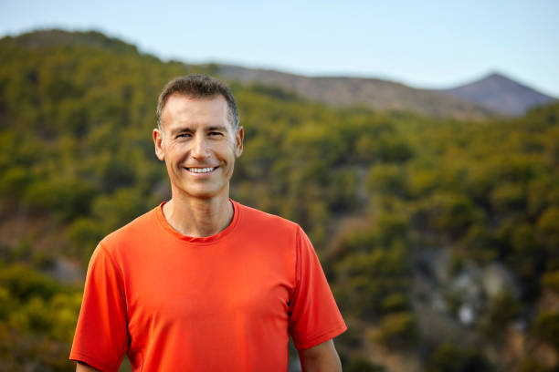 Portrait of smiling mature man against mountain stock photo