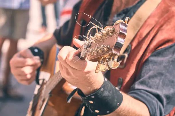 Photo of street musician playing mandolin through the streets of a city. horizontal.