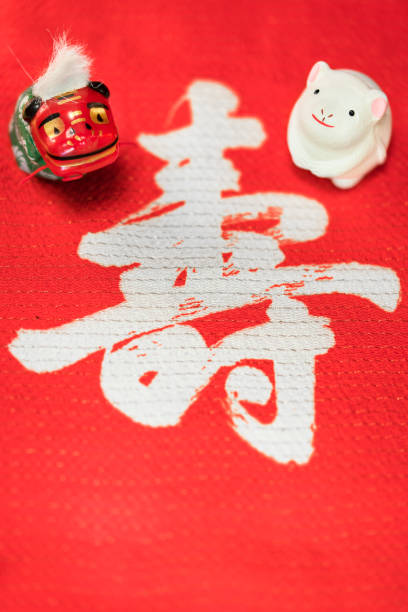 A Japanese greeting card with a cute rat figurine for the 2020 year of the mouse and a Folklore animal figurine depicting a Shishimai lion on a red cloth decorated with the Japanese Kotobuki ideograph which means longevity. una tarjeta de felicitación japonesa con una linda figura de rata para el año 2020 del ratón y una figura de animal folclórica que representa a un león shishimai en un paño rojo decorado con el ideógrafo kotobuki japonés que significa longevidad.