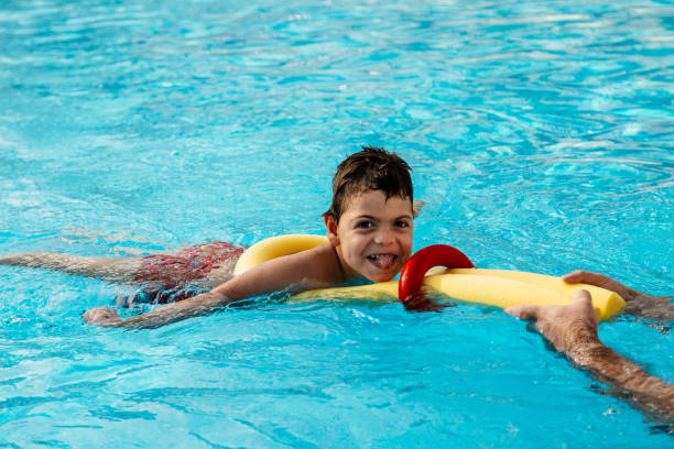 menino pequeno que joga na associação com flutuador - child swimming pool swimming little boys - fotografias e filmes do acervo