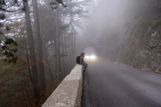 Photo of Car driving through a natural stone tunnel in the mountain forest