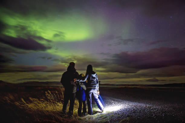 çocuklu güzel aile, açık bir gökyüzü gecesinde i̇zlanda'da çekilen aurora borealis ile gökyüzünü izliyor - astronomi fotoğraflar stok fotoğraflar ve resimler