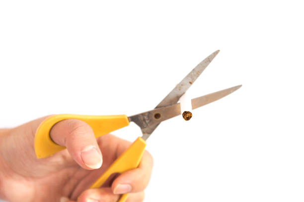 istock Studio shot selective focus Asian man hand cuts cigarette with scissors isolated 1182035103