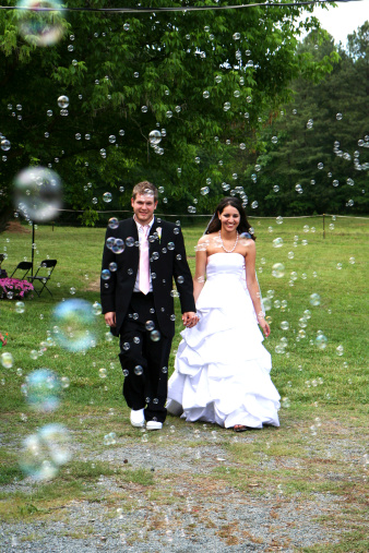 A bride and groom walk through bubbles after their wedding.