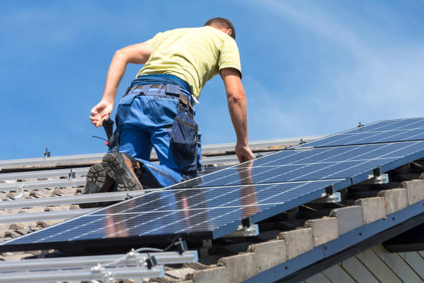 istock Low Angle View Of Man Installing Solar Panels On Roof Against Sky 1182040455