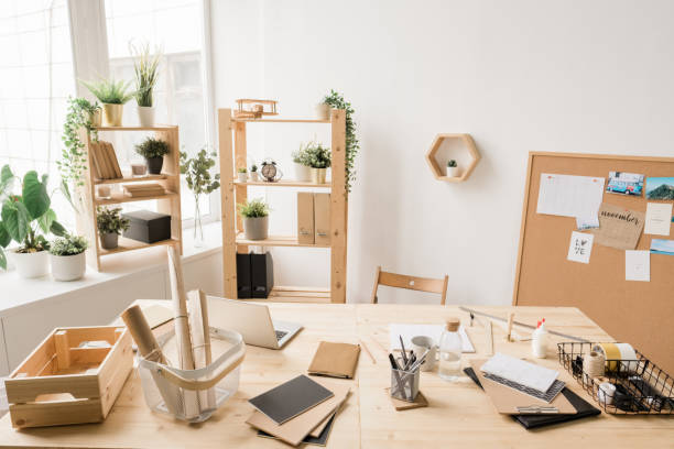 istock Part of studio interior with desk by window and various stuff for work 1182046166