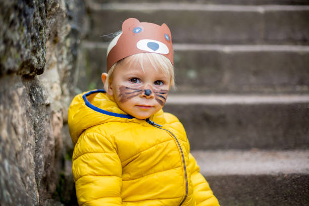 Adorable blond toddler child with bear mask and painted face Adorable blond toddler child with bear mask and painted face, smiling cat face paint stock pictures, royalty-free photos & images