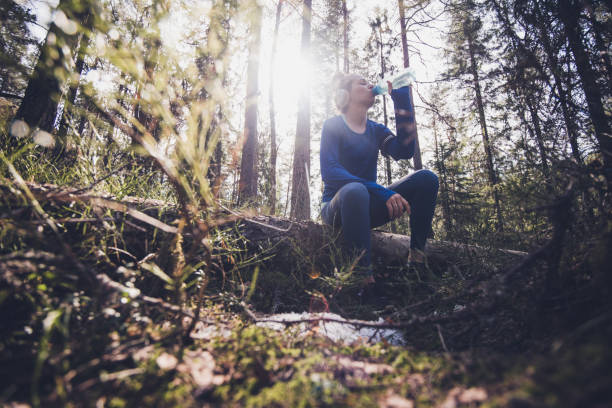 istock Young beautiful female sitting on the three and drinking water. 1182048681