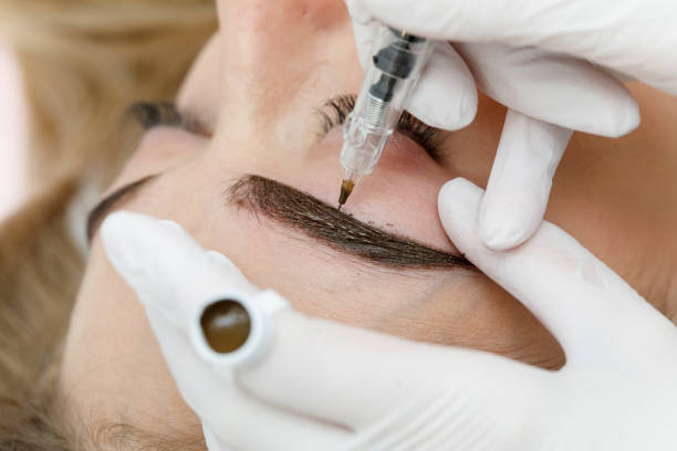 istock Permanent makeup, tattooing of eyebrows. Cosmetologist applying make up 1182051051