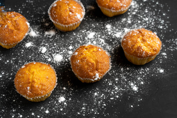 istock Appetizing muffins stand on a table top view. Traditional pastries on a dark background minimalism. 1182051093