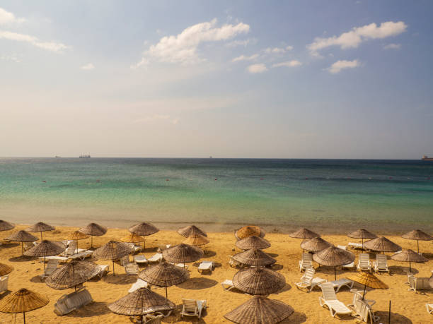 istock Yellow lounge chairs and parasols in a row on beach 1182053751