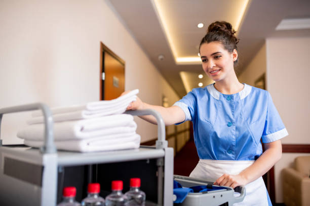 istock Young smiling chamber maid taking white clean towel from top of stack 1182054682