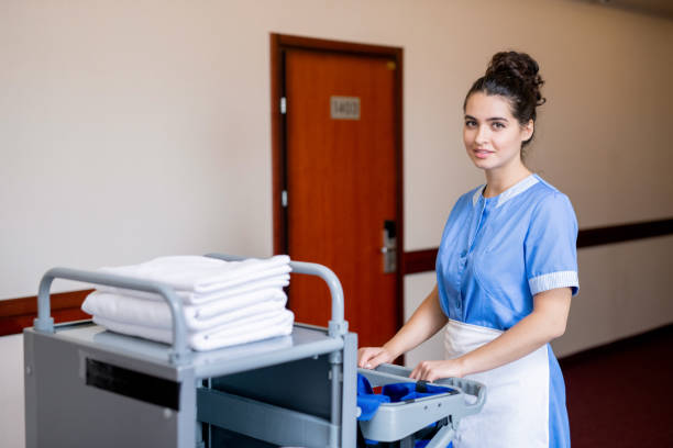 istock Chamber maid pulling cart with clean towels while moving along corridor in hotel 1182054686
