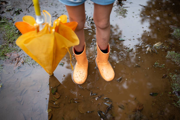 istock Child wearing rain boots playing in a puddle 1182054906
