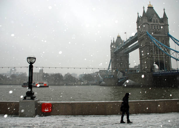 istock Person walking and the River Thames footpath past London's Tower Bridge during the snowfall 1182054939