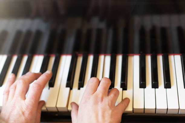 istock Musician's hands playing a magnficent grand piano keyboard 1182054995