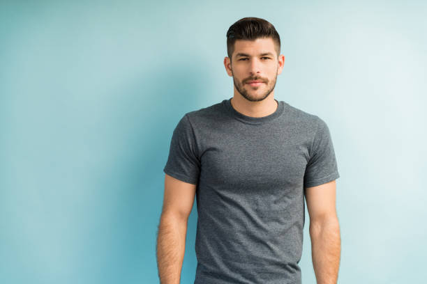 guapo hombre latino contra fondo turquesa - gray shirt fotografías e imágenes de stock