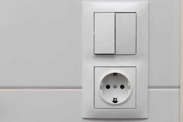 istock Close up view of white light swithch and socket pair on white tile. Building construction elements concept. Interior. Design. 1182055270