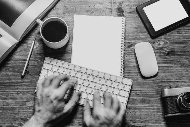 New year Goals Concept. Notepad with To do list, tablet, pen, keyboadr and cup of coffee or tea. Top view flat lay. Workplace of freelance designer, blogger, photographer. Black and white image