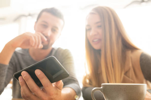 istock Young man holding smartphone while showing curious stuff to his girlfriend 1182060049