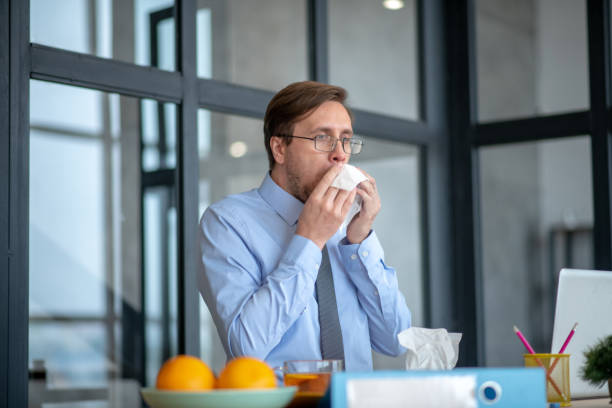 istock Businessman sneezing all day at work and feeling dizzy 1182061447