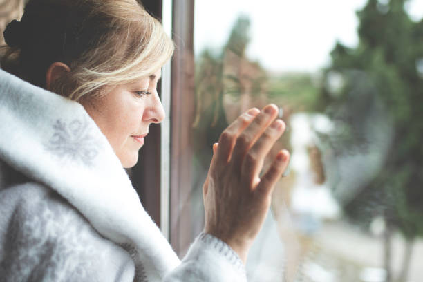 istock Alone woman day dreaming by the window 1182061592