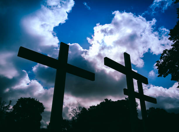 istock Three crosses silhouetted against a cloudy sky 1182063322