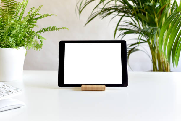 Blank white screen on portable tablet device on modern office desk
